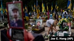 Natalia Zaicenko, în vârstă de 60 de ani, îngrijește mormântul fiului ei, un soldat ucrainean care a fost ucis în războiul împotriva Rusiei, la Kiev, pe 3 august.