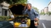 A taxi driver in Iran splashing water on her face on a hot day