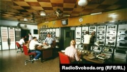 Сотрудники корпорации Радио Свободная Европа / Радио Свобода в технической комнате с панелью управления, откуда записи радиопередач на разных языках транслировали на территорию СССР и страны Восточной Европы, 1970-е