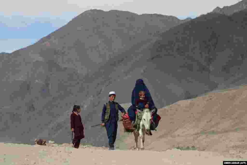 O femeie îmbrăcată în burqa și copii săi, pe un drum din provincia afgană Badakhshan.
