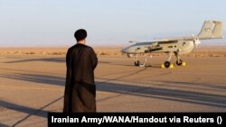 یک روحانی در جریان یک رزمایش نظامی در نقطهای نامعلوم از ایران رو به یک پهپاد ایستاده است
