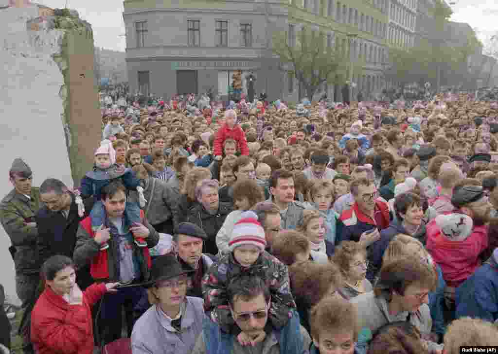 Oamenii trec printr-o breșă în zid pe 11 noiembrie, după ce soldaților est-germani li s-a ordonat să se dea la o parte, punându-se astfel capăt în mod efectiv separării fizice dintre Berlinul de Est și Berlinul de Vest.&nbsp;