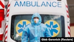 UKRAINE -- A medical worker wearing protective gear stands next to an ambulance outside a hospital for patients infected with the coronavirus disease (COVID-19) in Kyiv, November 24, 2020
