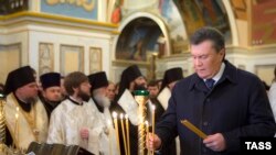 Президент Виктор Янукович Биримдик күнүнө карай чиркөөдө өткөрүлгөн зыяпатта шам койууда. Киев, 22-январь
