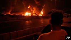 Мужчына назірае за полымем над нафтасховішчам пасьля меркаванага ізраільскага авіяўдару ў Тэгеране 16 чэрвеня