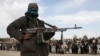 A Taliban fighter and onlookers witness the execution of three men in Ghazni Province in 2015.
