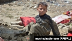 په خوست کې یو ماشوم په ورښتونو کې له خپل زیانمن شوي کور سره نېږدې ناست دی - د اګست شپږمې انځور.