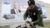 Член на московски воен клуб склопува калашников за време на вежба, додека зад него се гледа постер со ликот на рускиот претседател Владимир Путин