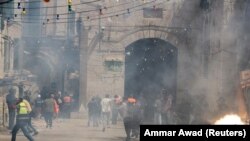 Palestinezët duke ikur pasi policia izraelite hedh gaz lotsjellës dhe granata tymuese në drejtim të tyre. Jerusalem, 10 maj, 2021.
